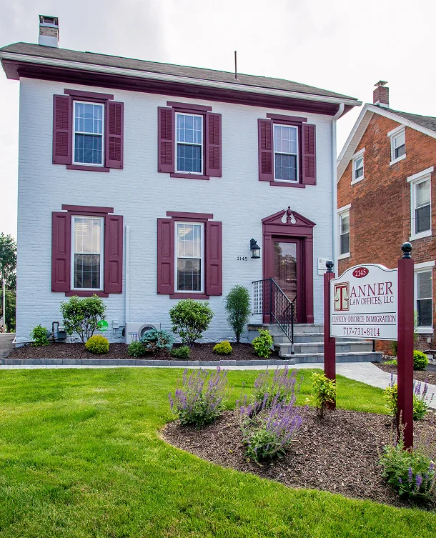 Tanner Law Offices building with maroon shutters and entrance, featuring a front lawn and sign displaying the law firm's name and contact information