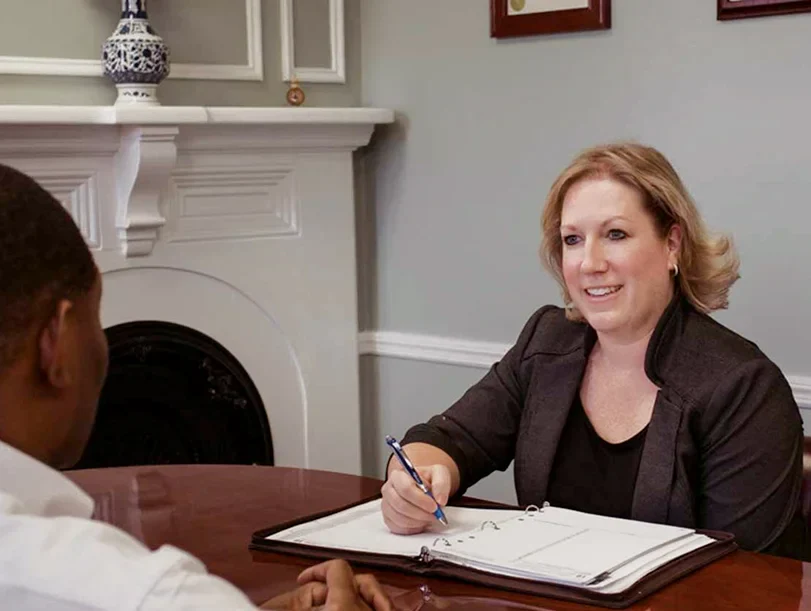 Attorney Tabetha A. Tanner sitting at a desk with a client, taking notes and smiling during a consultation